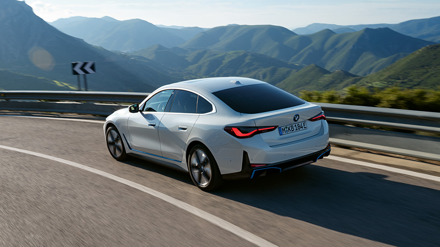 BMW i4 eDrive40 G26 2021 sedd snett bakifrån körandes BMW i4 eDrive40 G26 2021 Mineralvit sedd snett bakifrån körande