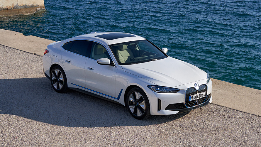 BMW i4 eDrive40 G26 2021 sedd snett framifrån på kaj BMW i4 eDrive40 G26 2021 Mineralvit sedd snett framifrån på kaj