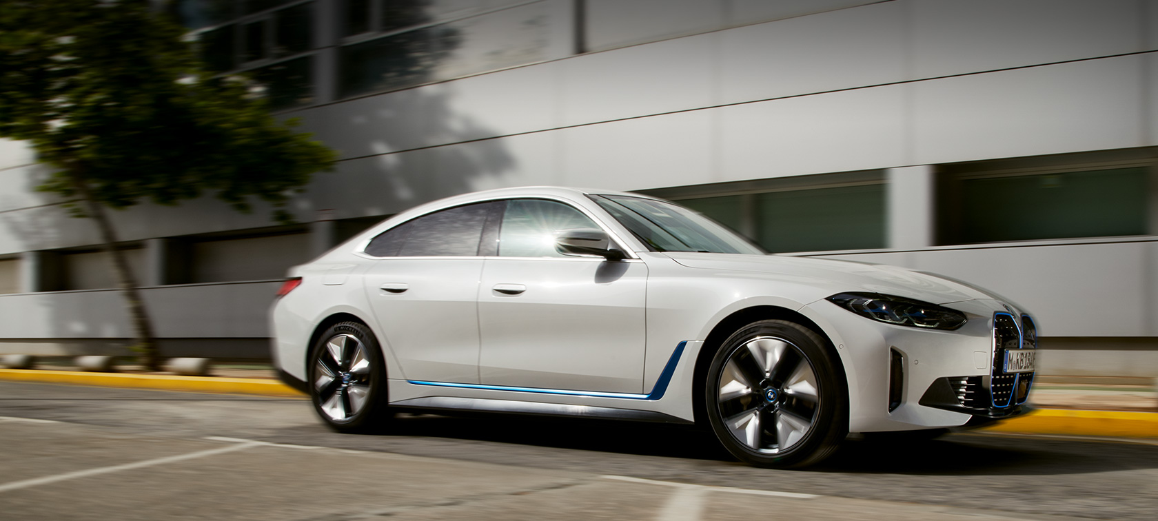 BMW i4 eDrive40 G26 2021 sedd snett från sidan körandes framför byggnad BMW i4 eDrive40 G26 2021 sedd snett från sidan körandes framför byggnad