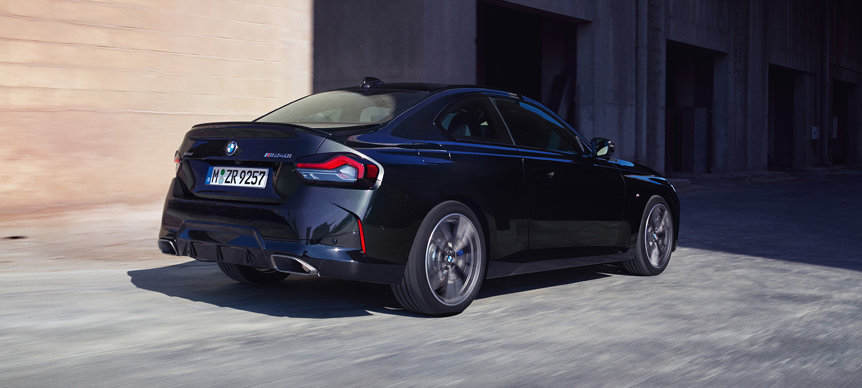 BMW M240i xDrive Coupé G42 2021 sedd snett bakifrån BMW M240i xDrive Coupé G42 2021 Safirsvart metallic, sedd snett bakifrån körandes