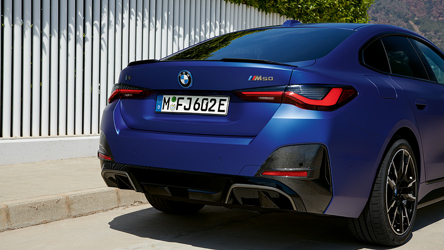 BMW i4 M50 G26 2021 BMW Individual Frozen Portimao Bl&aring; metallic sedd snett bakifr&aring;n parkerad vid vitt staket