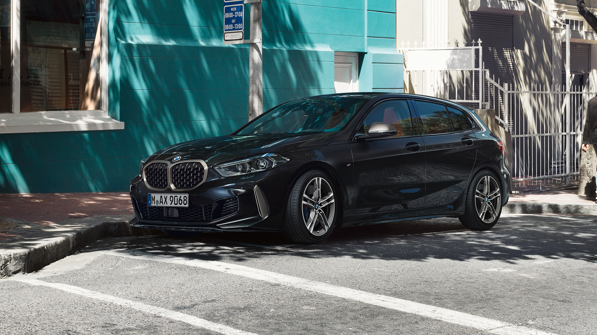 BMW M135i xDrive, trefjärdedelsvy från sidan. BMW M135i xDrive i safirsvart metallic, trefjärdelsvy från sidan, parkerad.