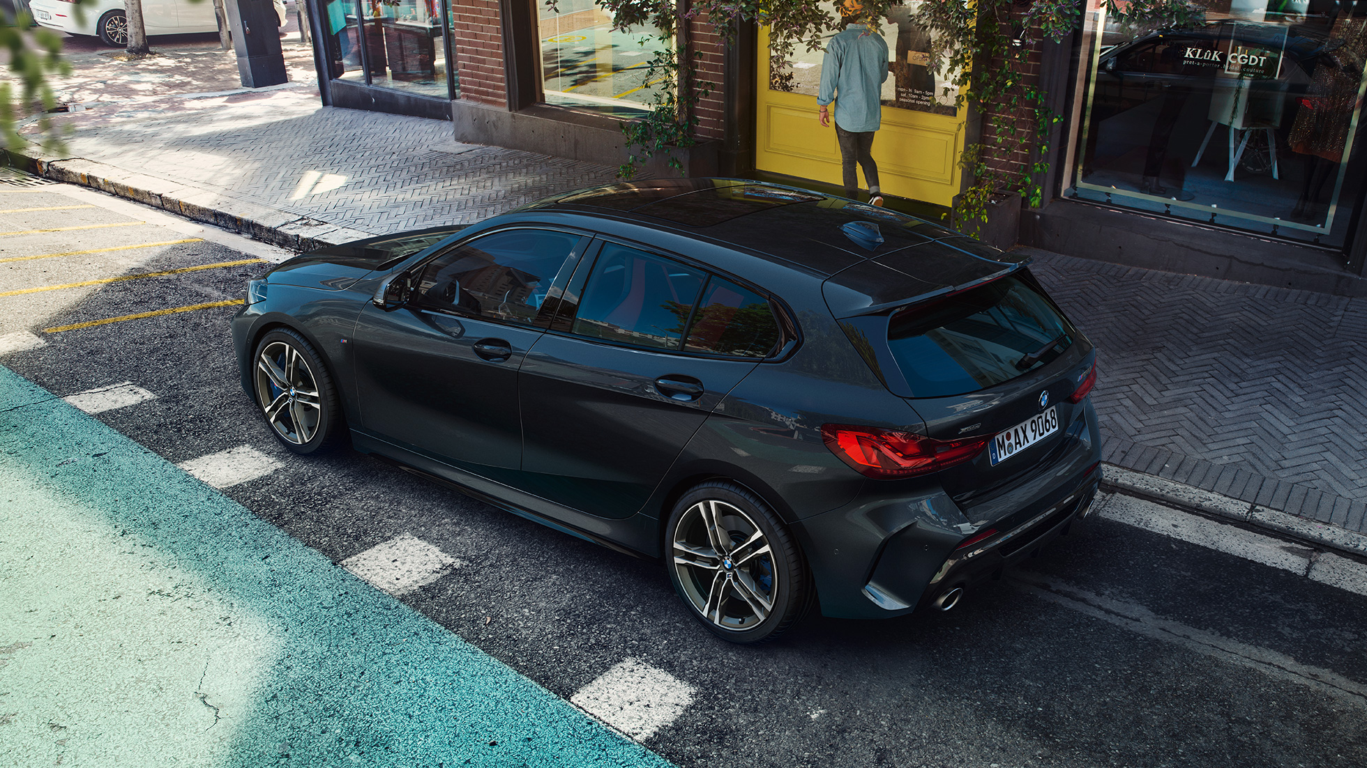 BMW M135i xDrive som parkeras. BMW M135i xDrive i safirsvart metallic som parkeras, sedd ur fågelperspektiv från sidan.