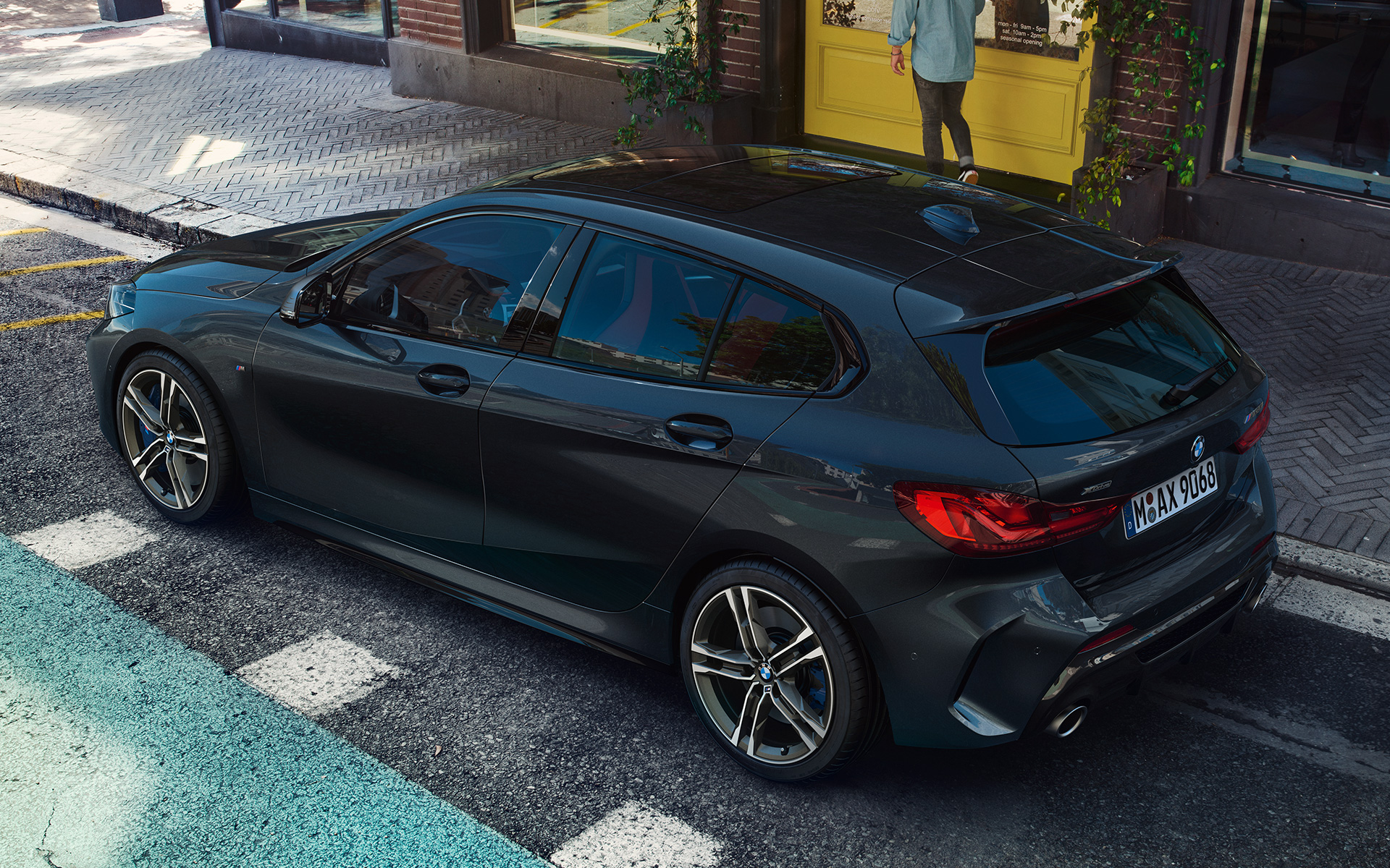 BMW M135i xDrive (F40) i Safirsvart metallic som parkeras, sedd från sidan ur fågelperspektiv