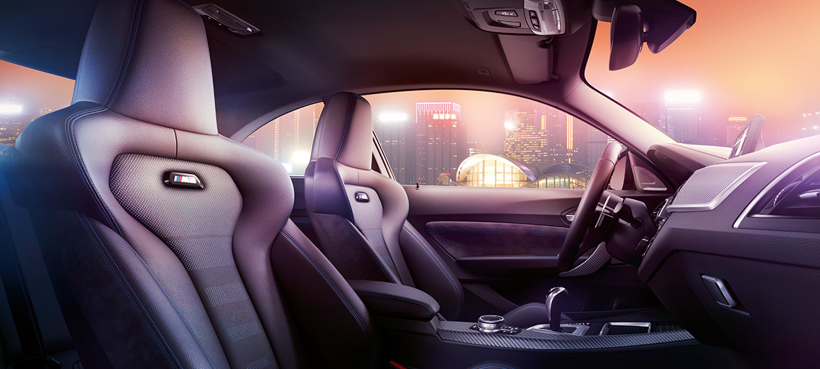 BMW M2 Competition sportstolar Cockpit och M sportstolar i BMW M2 Competition, nattlig skyline i bakgrunden.