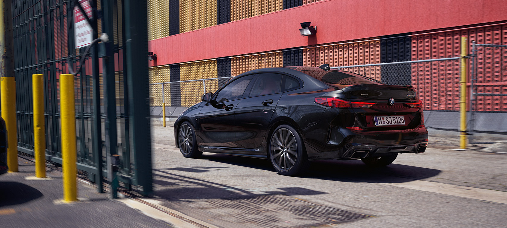 BMW M235i xDrive Gran Coupé F44 sedd snett bakifrån körandes BMW M235i xDrive Gran Coupé F44 Safirsvart metallic sedd snett bakifrån körandes