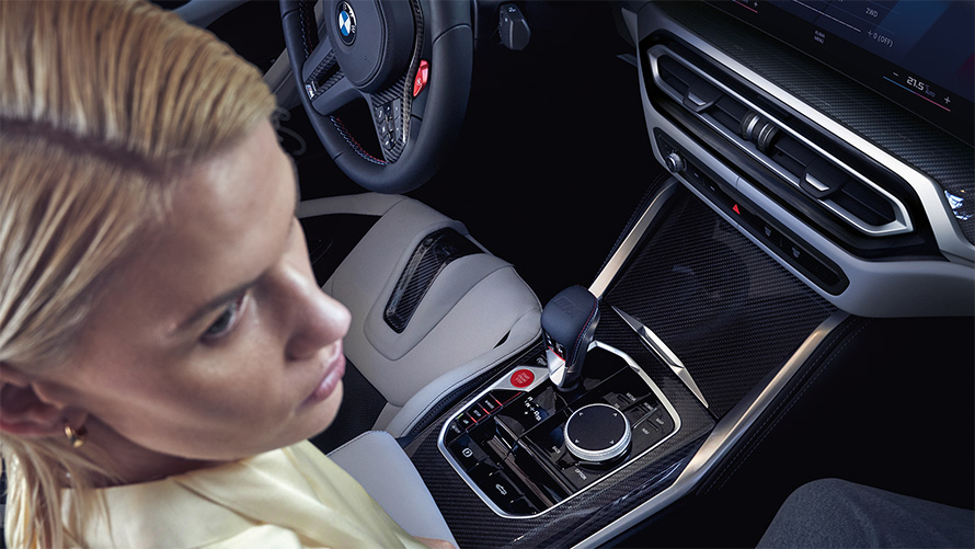 BMW M4 Competition Cabriolet med M xDrive G83 Interiör 2021 Mittkonsol BMW M4 Competition Cabriolet med M xDrive G83 2021 Mittkonsol och en kvinna i passagerarstolen