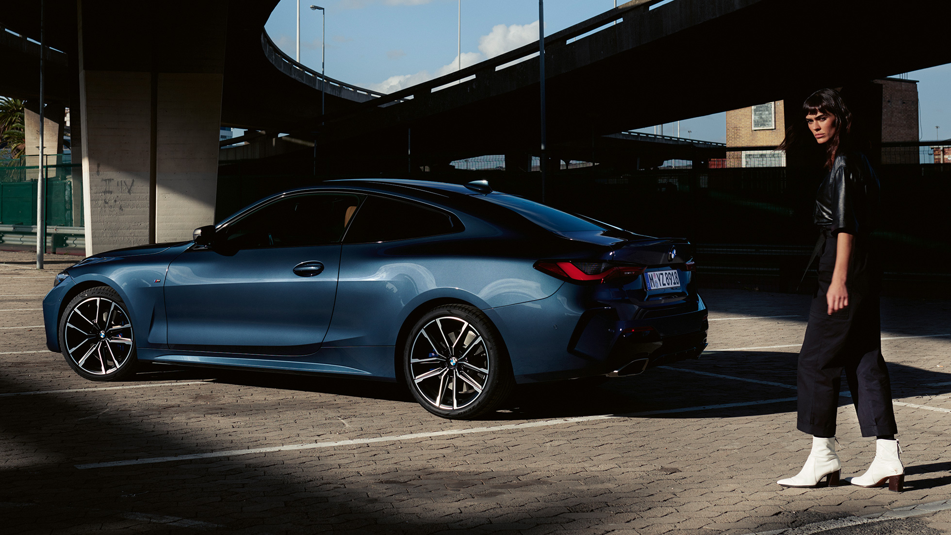 Vy snett bakifrån med modell BMW M440i xDrive Coupé G22 2020 BMW M440i xDrive Coupé Arctic Race Blue metallic G22 2020 sedd snett bakifrån med modell