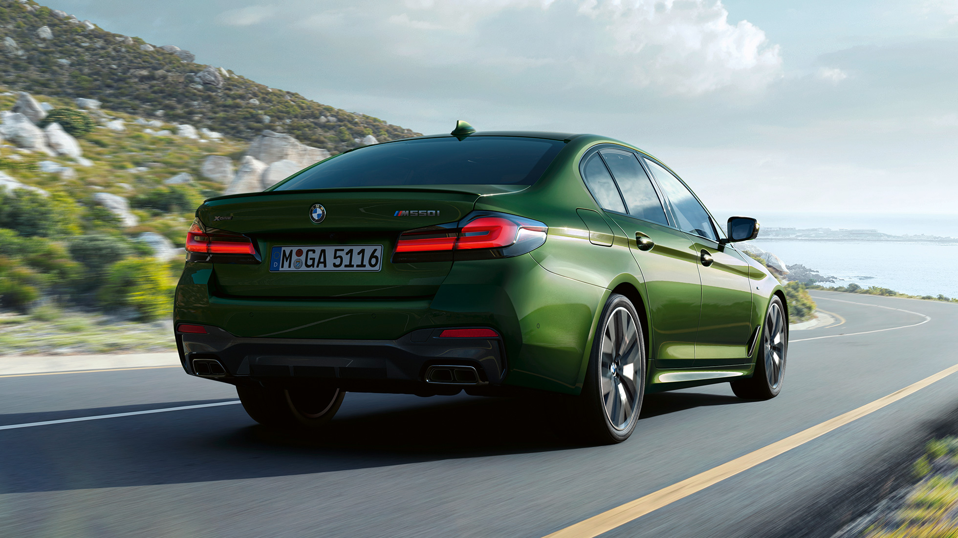 BMW M550i xDrive Sedan G30 LCI Facelift 2020 vy av bakpartiet BMW M550i xDrive Limousine G30 LCI Facelift 2020 BMW Individual Verde Ermes metallic sedd bakifrån körandes i stan