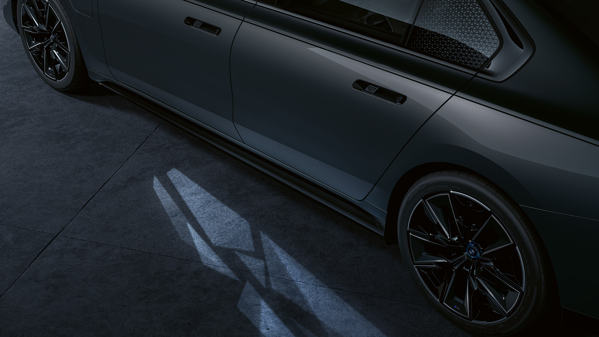 Ljuskoncept BMW M760e xDrive Sedan G70 Ljuskoncept BMW M760e xDrive Sedan G70 BMW Individual tvåtonslack Safirsvart metallic BMW Individual Dravitgrå metallic närbild med tänd Welcome Light Carpet