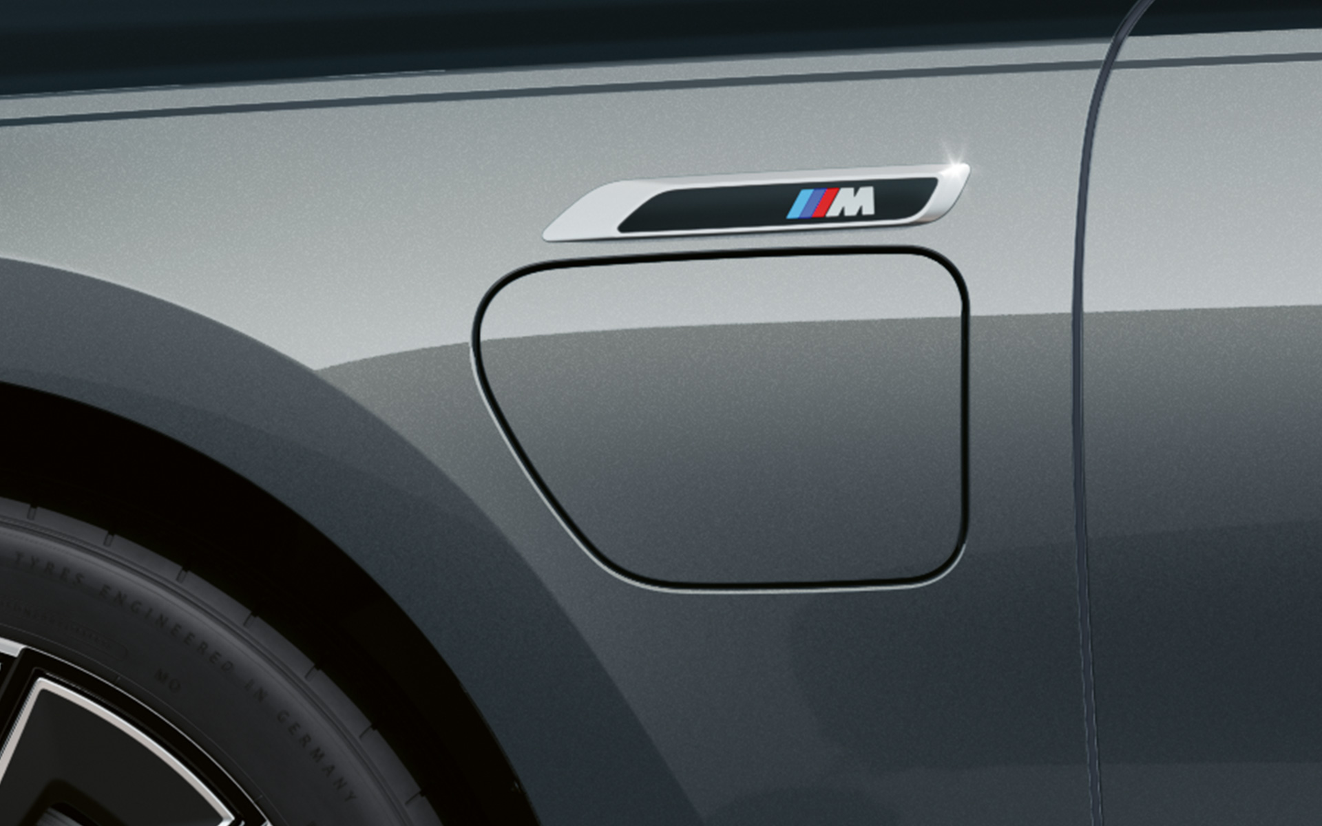 M emblem BMW M760e xDrive Sedan G70 M Performance-paket BMW Individual tvåtonslack Safirsvart metallic BMW Individual Dravitgrå metallic närbild sedd från sidan
