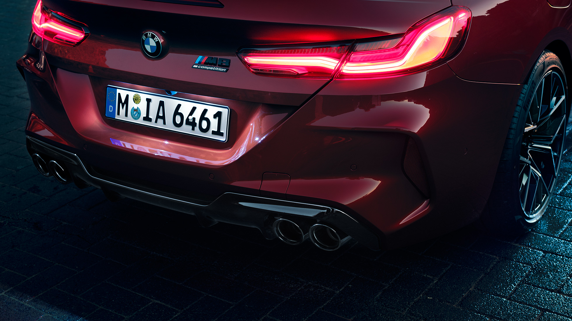 BMW M8 Competition Cabriolet, närbild på bakpartiet.. BMW M8 Competition Cabriolet i Motegi Rödmetallic, närbild på bakpartiet med LED-baklyktor och M8 Competition Badge.
