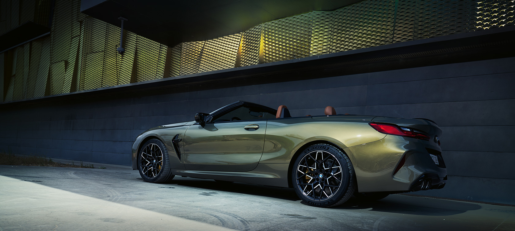 BMW M8 Competition Cabriolet F91 LCI Facelift 2022 BMW Individual Brass metallic sedd snett från sidan parkerad framför vägg