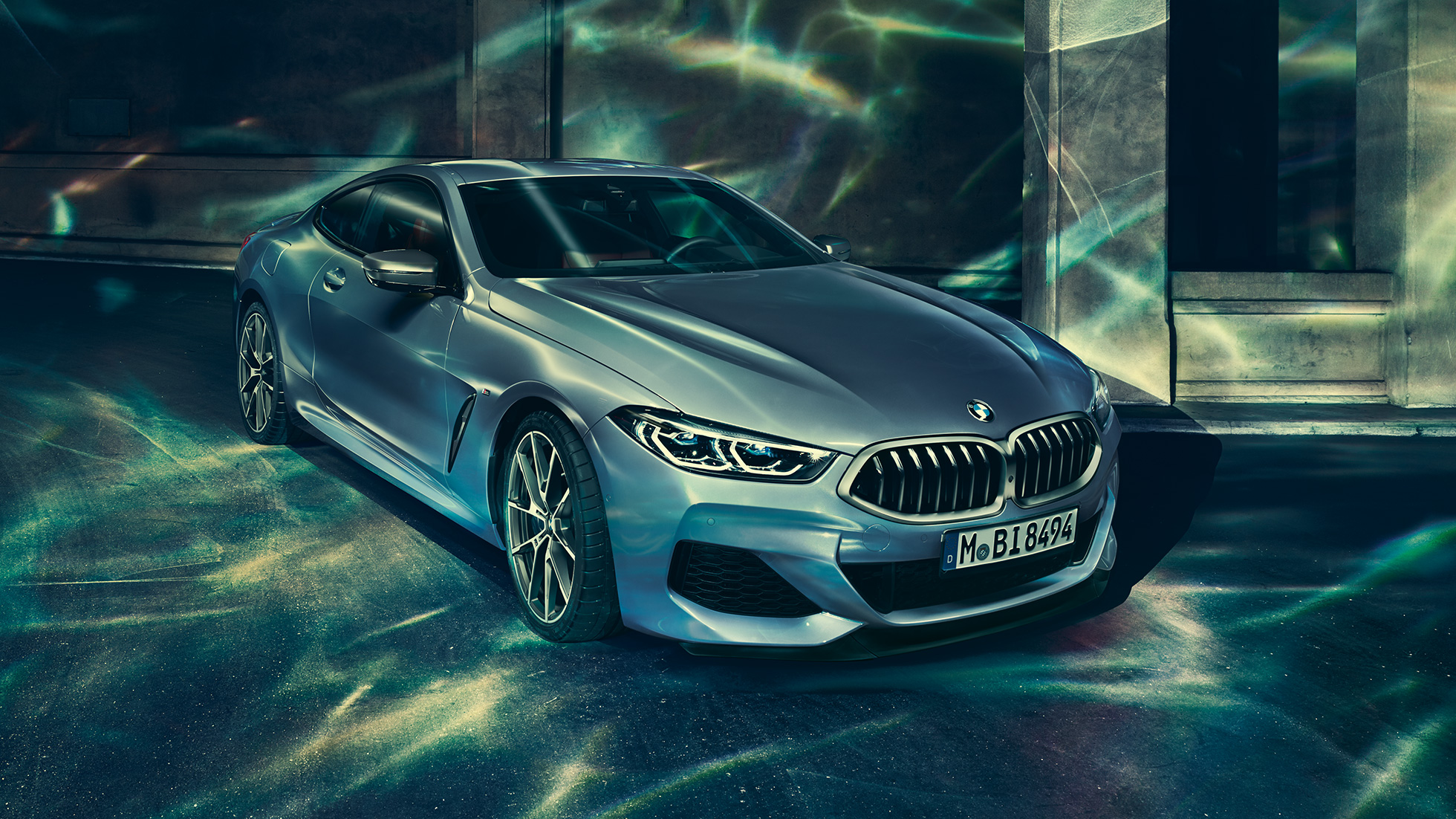 BMW M850i xDrive Coupé, trefjärdedelsvy framifrån från vänster. BMW M850i xDrive Coupé i Barcelona Blåmetallic, trefjärdedelsvy snett framifrån från vänster, parkerad framför byggnad.