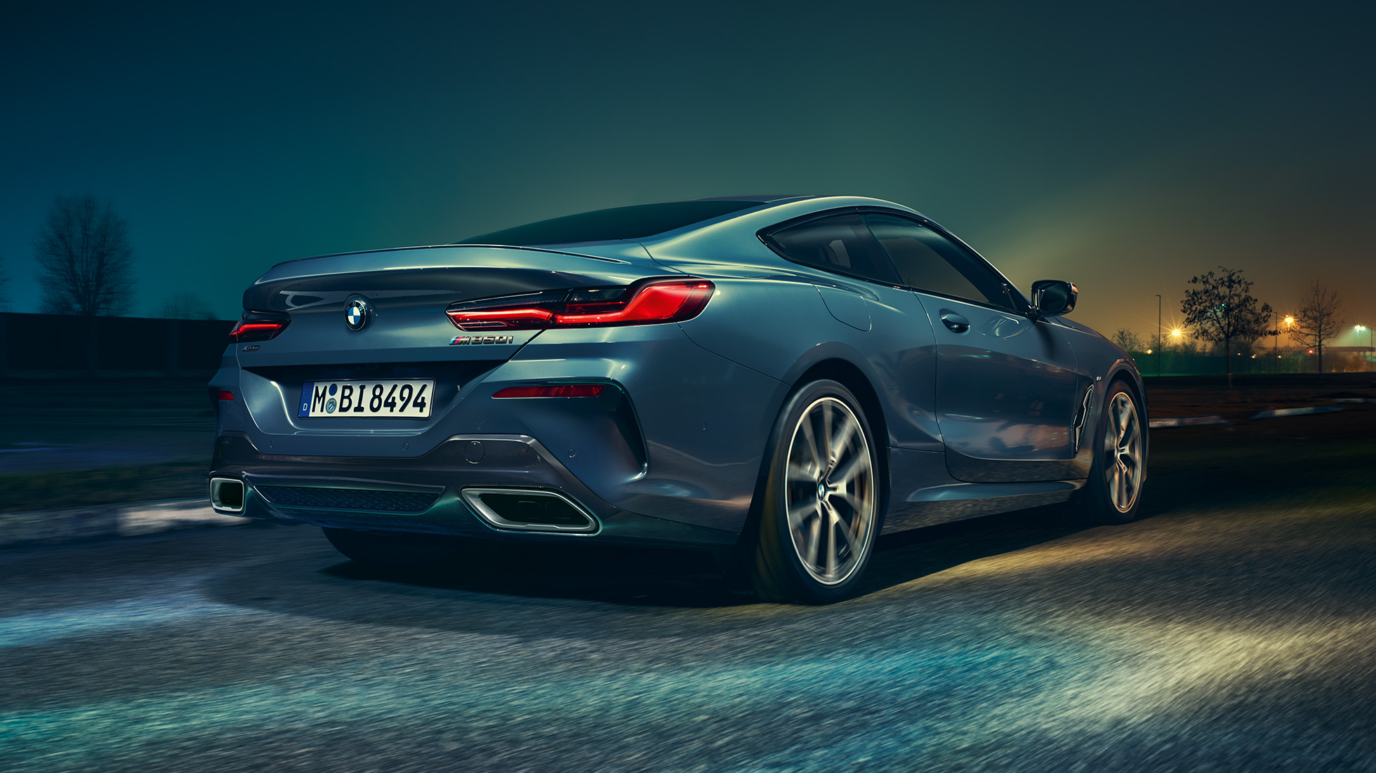 BMW M850i xDrive Coupé, sedd bakifrån. BMW M850i xDrive Coupé i Barcelona Blåmetallic, sedd bakifrån, körning på natten.