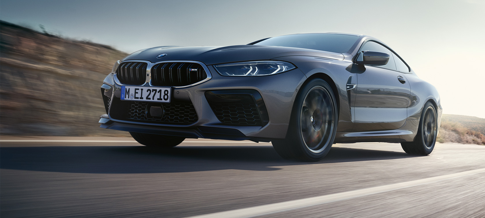 BMW M8 Coupé F92 LCI Facelift 2022 sedd snett från sidan körandes BMW M8 Coupé F92 LCI Facelift 2022 Skyscraper Grå metallic sedd snett från sidan körandes grodperspektiv