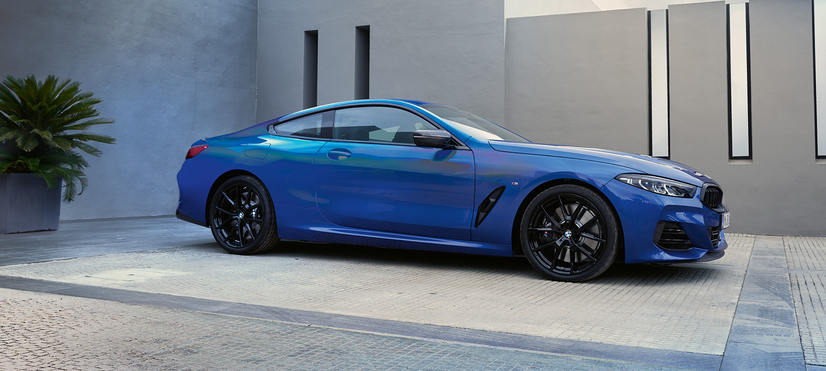 Sidvy BMW M850i xDrive Coupé G15 LCI Facelift 2022 BMW M850i xDrive Coupé G15 LCI Facelift 2022 M Portimao Blue metallic sidvy parkerad framför byggnad