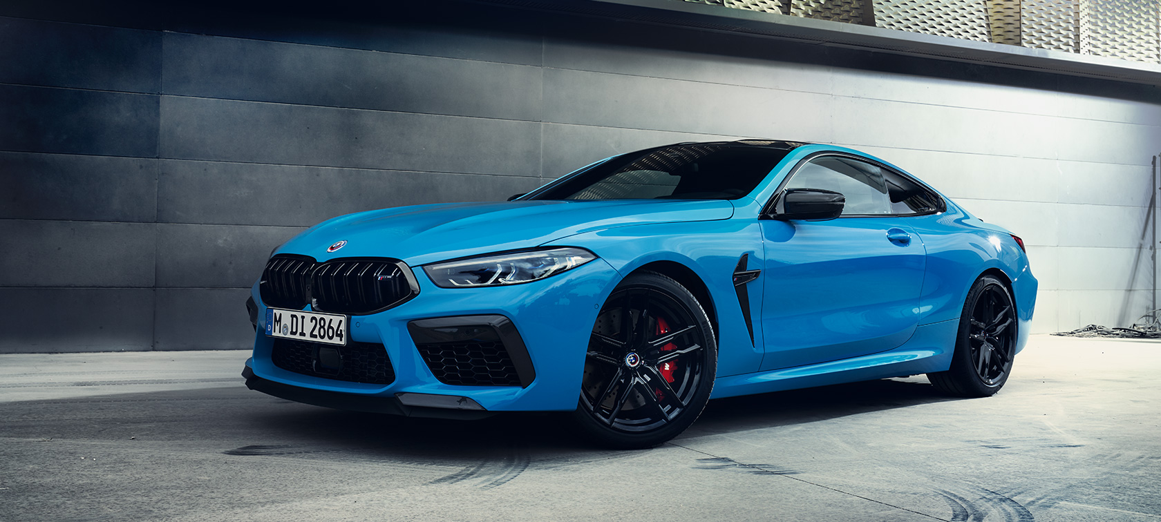 BMW M8 Competition Coupé F92 LCI Facelift 2022 Daytona Beach Blue standardlackering sedd snett från sidan parkerad framför vägg