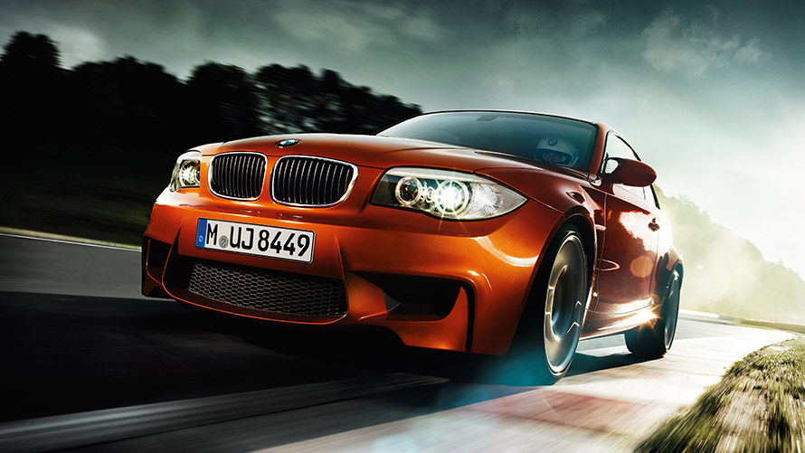 BMW 1-serie M Coupé E82 sedd snett framifrån körande på väg BMW M-modeller BMW 1-serie M Coupé E82 sedd snett framifrån körande på väg