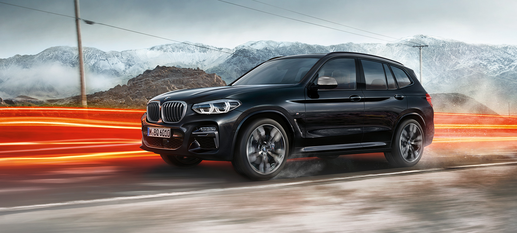 BMW X3 M40i och BMW X3 M40d, vy från sidan. BMW X3 M40i och BMW X3 M40d i Safirsvart metallic, kommer körande, Exteriör, vy från sidan berglandskap med ljusstrimmor.