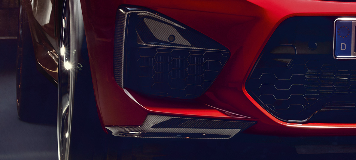 BMW X4 M Competition, infattningar i de utvändiga luftintagen och Aeroblades av kolfiber. BMW X4 M Competition i Torontoröd metallic, Exteriör, M Carbon exteriörpaket, infattningar i de utvändiga luftintagen och Aeroblades av kolfiber.