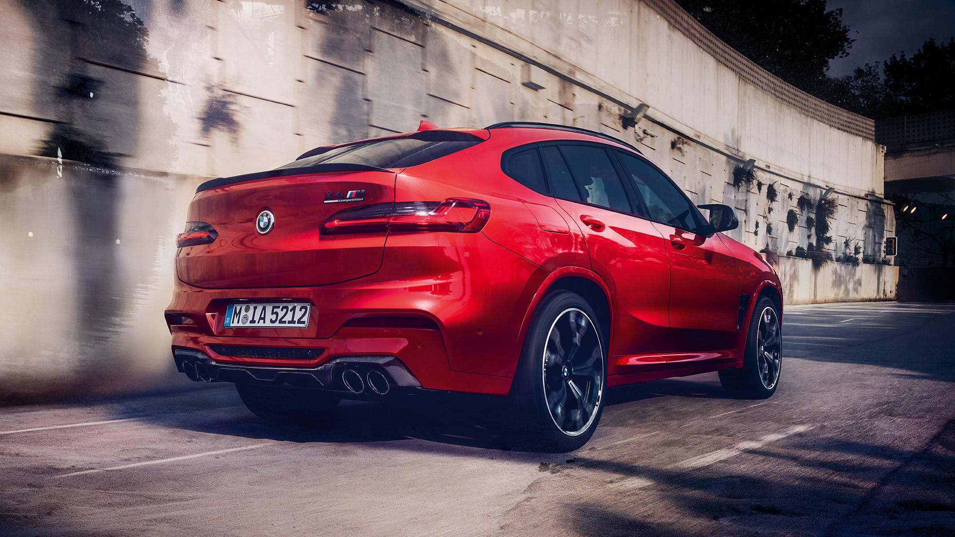 BMW M4 Competition, bakifrån från sidan. BMW X4 M Competition i Torontoröd metallic, Exteriör, bakifrån från sidan.