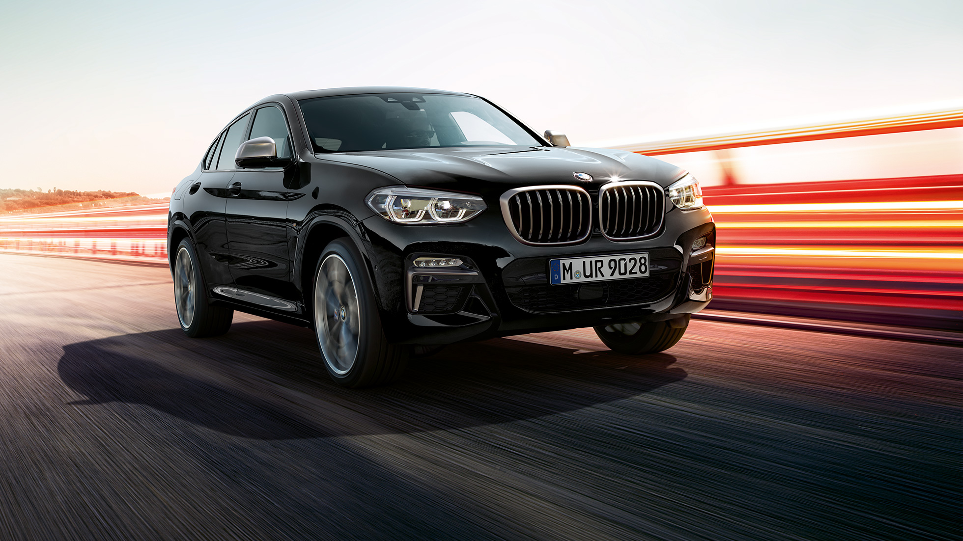 BMW X4 M40i och BMW X4 M40d, trefjärdedels vy framifrån. BMW X4 M40i och BMW X4 M40d i Safirsvart metallic, Exteriör, trefjärdedels vy framifrån från vänster med ljusstrimmor.