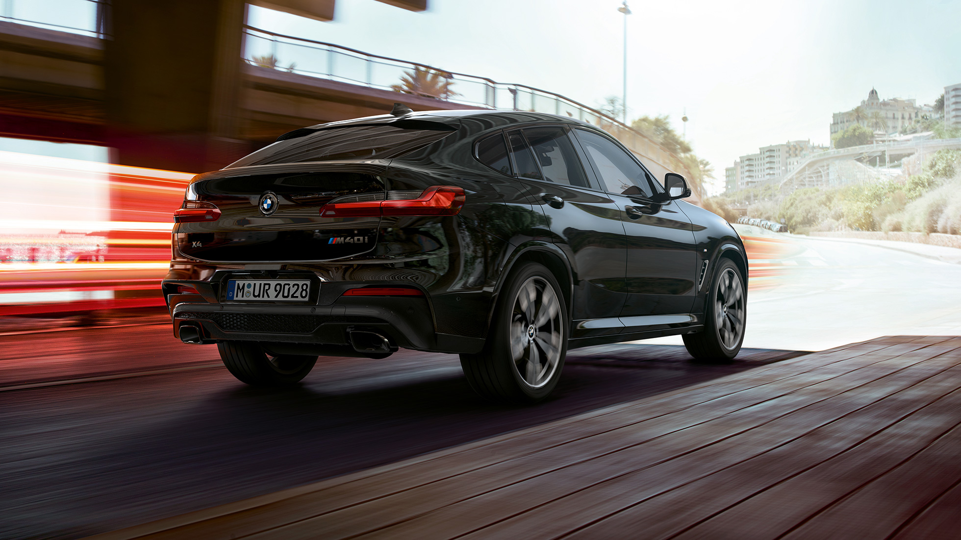 BMW X4 M40i, Trefjärdedels vy bakifrån. BMW X4 M40i i Safirsvart metallic, Exteriör, trefjärdedels vy bakifrån från höger med ljusstrimmor.