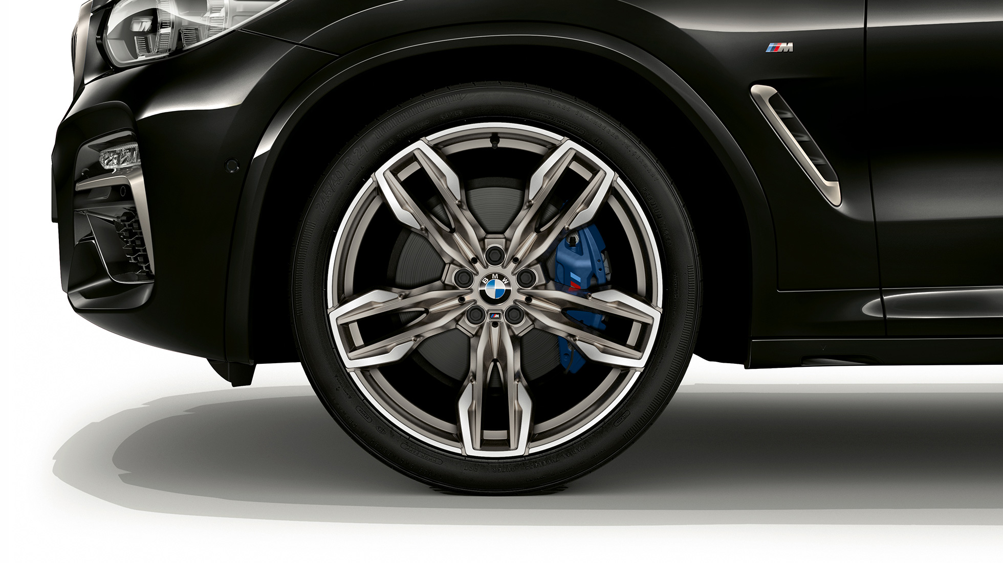 BMW X4 M40i och BMW X4 M40d, 21-tums M lättmetallfälgar. BMW X4 M40i och BMW X4 M40d i Safirsvart metallic, Exteriör, vy från sidan med 21-tums M lättmetallfälgar i dubbeleker-design.