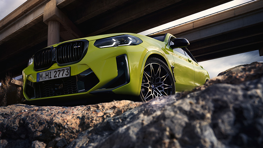 BMW X4 M Competition F98 LCI Facelift 2021 Sao Paulo-gul sedd snett underifrån från sidan körandes under broar.