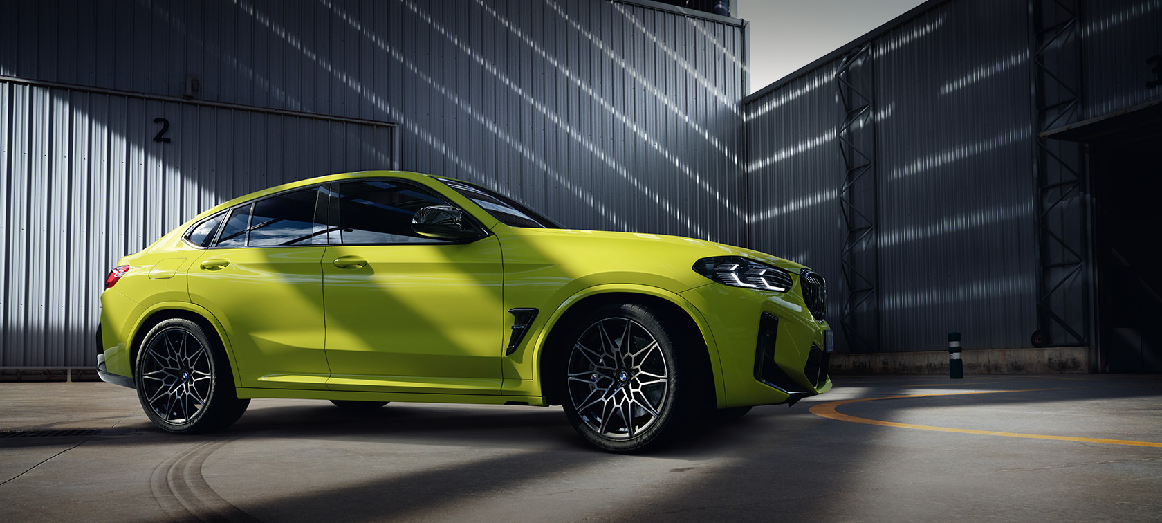 BMW X4 M Competition F98 LCI Facelift 2021 Sao Paolo-gul sedd från sidan i utställningshallen
