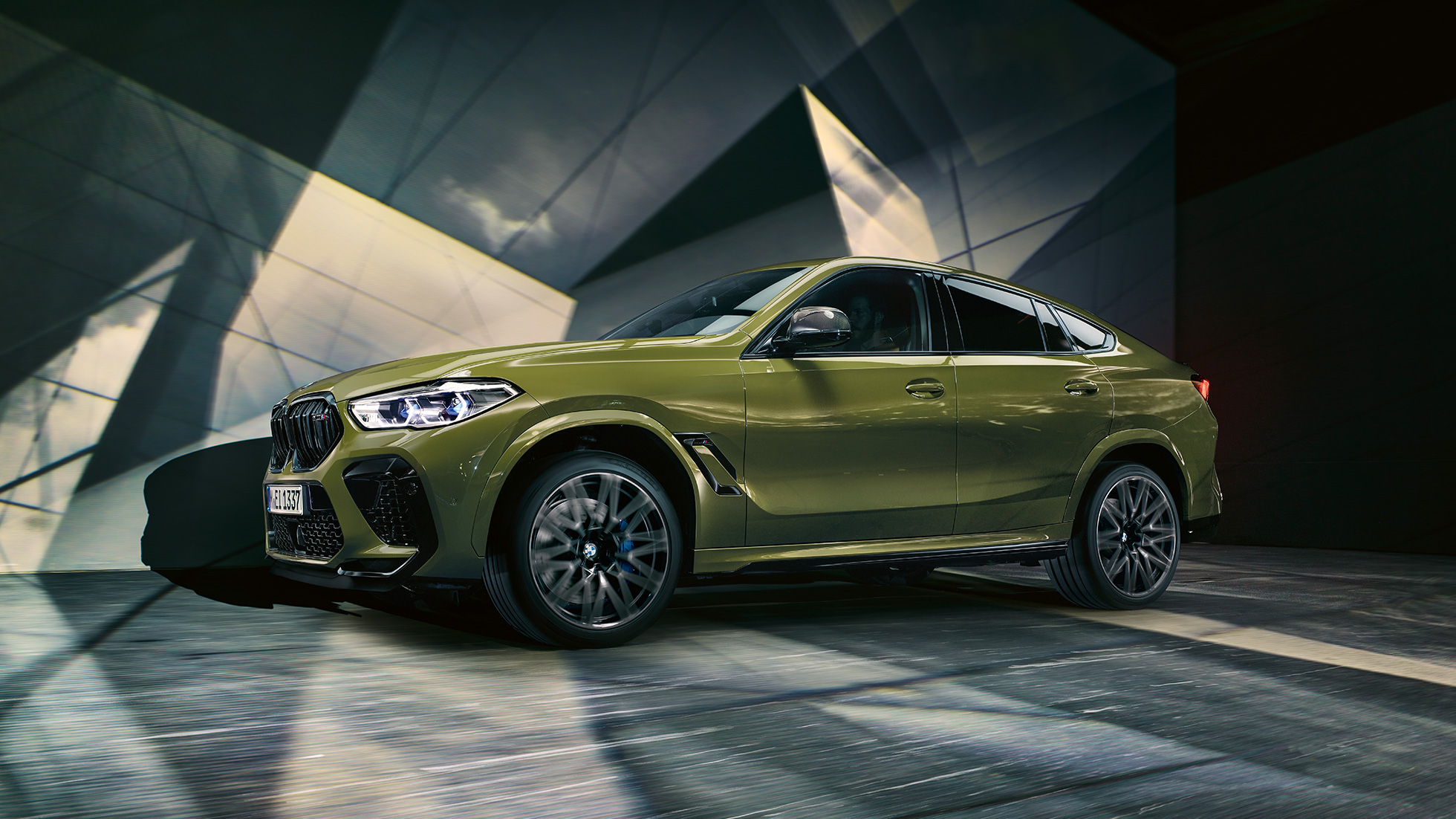 BMW X6 M Competition, vy från sidan. BMW X6 M Competition med M lättmetallfälgar F96 BMW Individual speciallack Urban Green trefjärdedelsvy bakifrån