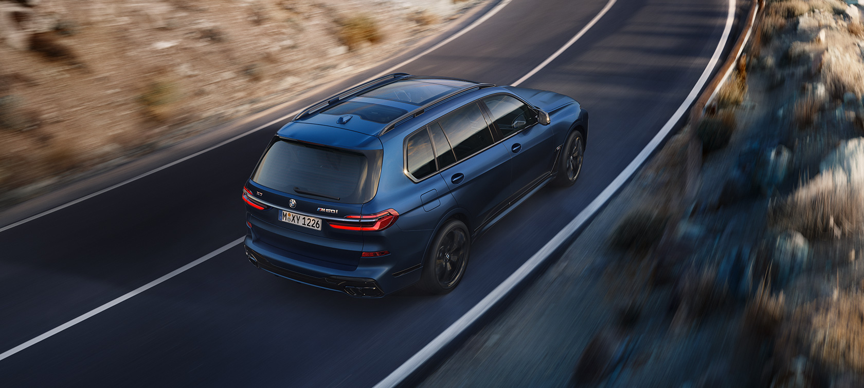 BMW X7 M60i G07 LCI Frozen Marina Bay Blue sedd snett bakifrån ur fågelperspektiv körande BMW X7 M60i G07 LCI Frozen Marina Bay Blue sedd snett bakifrån ur fågelperspektiv körande på väg