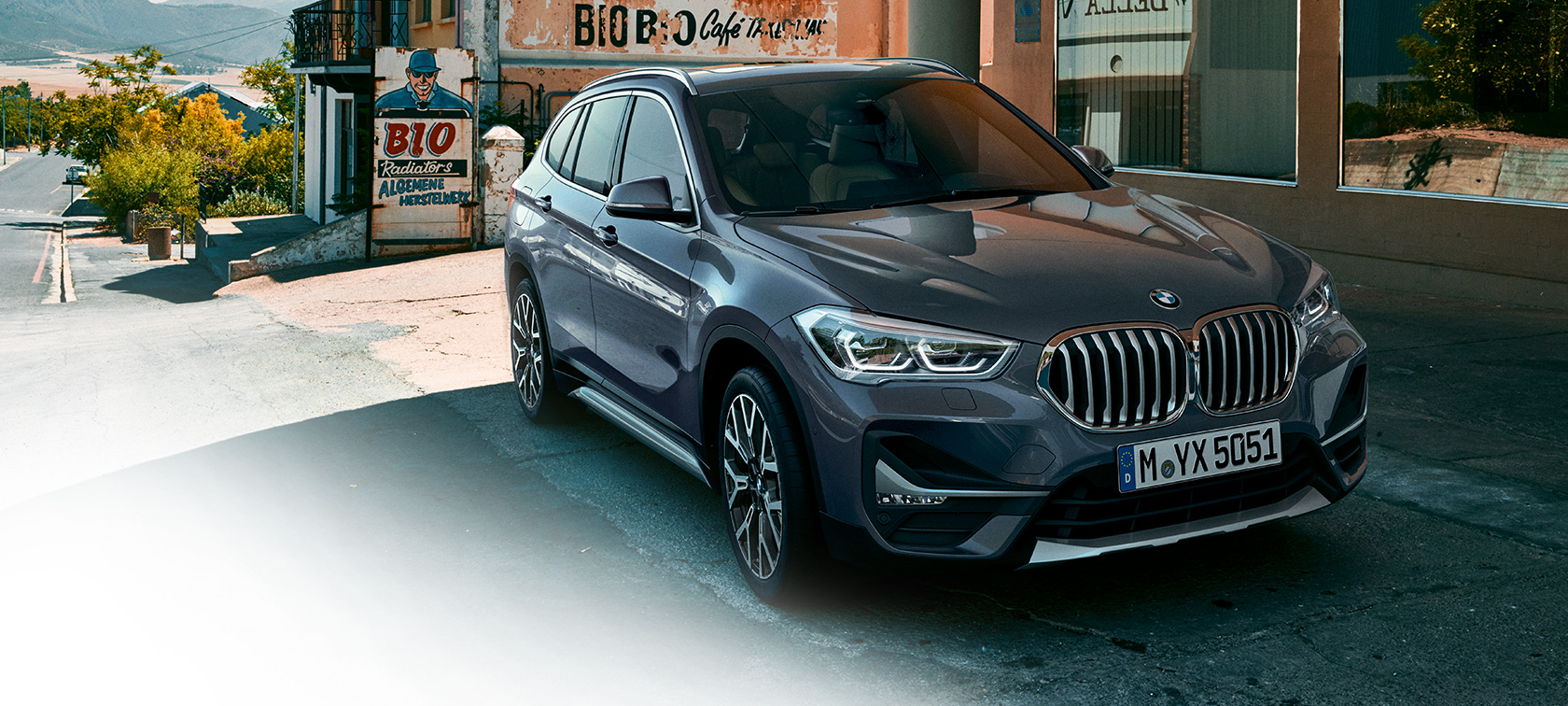BMW X1, trefjärdedelsvy framifrån. BMW X1, trefjärdedelsvy framifrån, parkerad framför stadsmiljö.