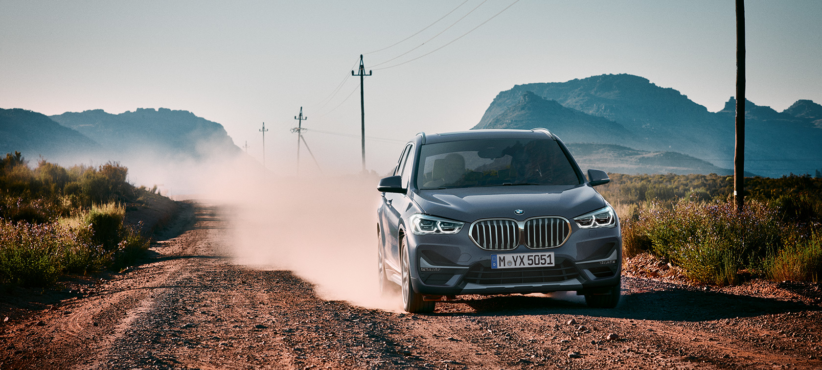 BMW X1, trefjärdedelsvy bakifrån. BMW X1, trefjärdedelsvy bakifrån, körande framför berglandskap.