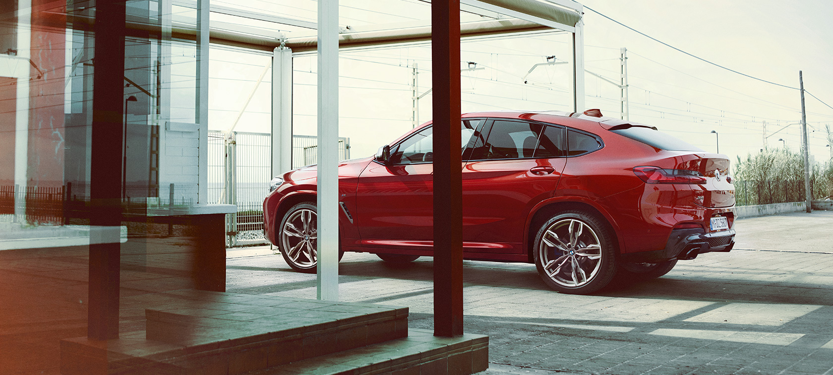 BMW X4 sedd från sidan BMW X4 M40i G02 2018 Flamencoröd briljanteffekt sedd från sidan parkerar