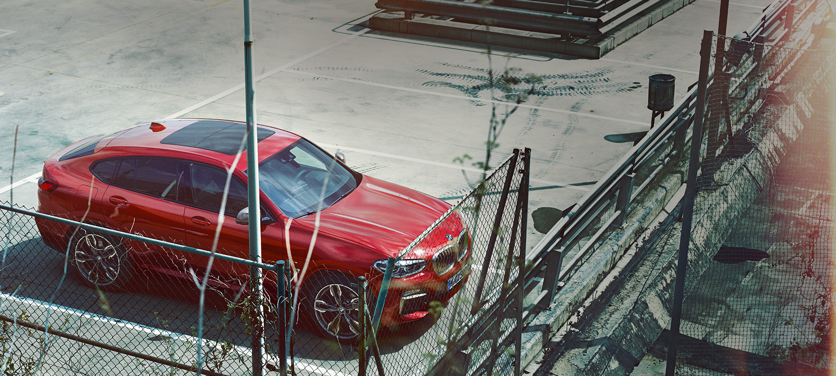 BMW X4 parkeras BMW X4 G02 2018 Flamencoröd briljanteffekt parkeras i parkeringshus fågelperspektiv
