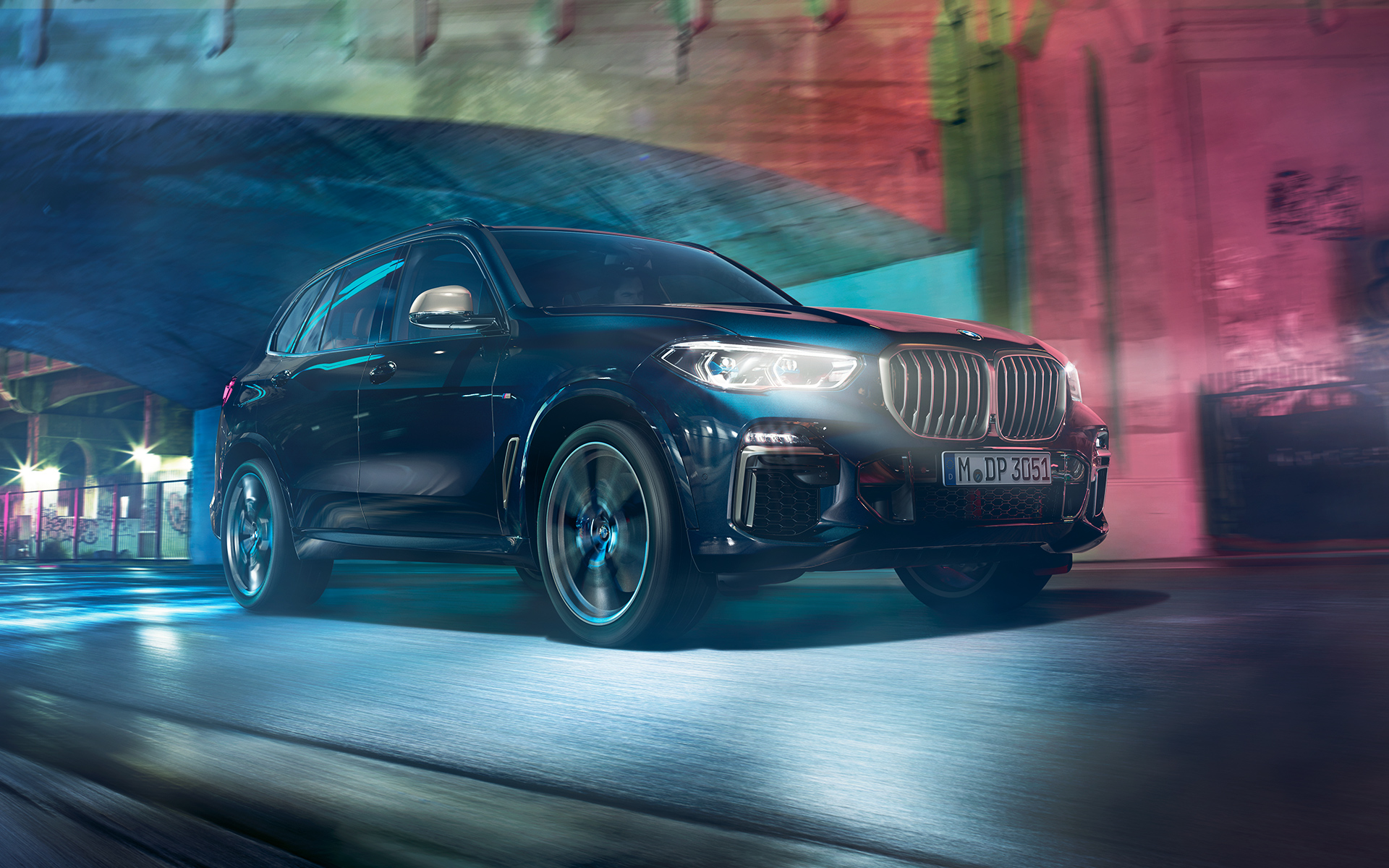 BMW X5 M50d i full frihet Foto på körande BMW X5 M50d framför urban kuliss på natten