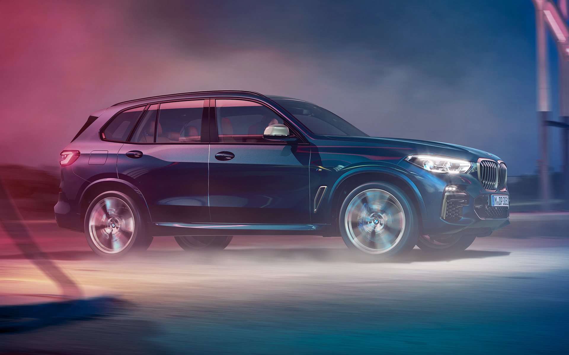 Körande BMW X5 M50d Foto på körande BMW X5 M50d framför stadskuliss på natten