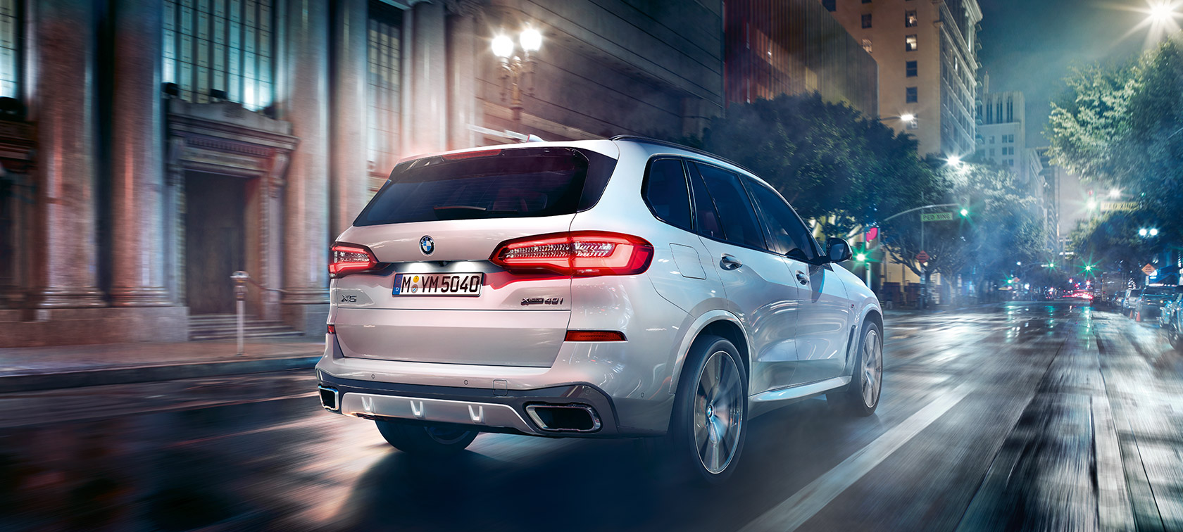 BMW X5 trefjärdedelsvy bakifrån körandes BMW X5 G05 2018 Mineralvit metallic trefjärdedelsvy bakifrån