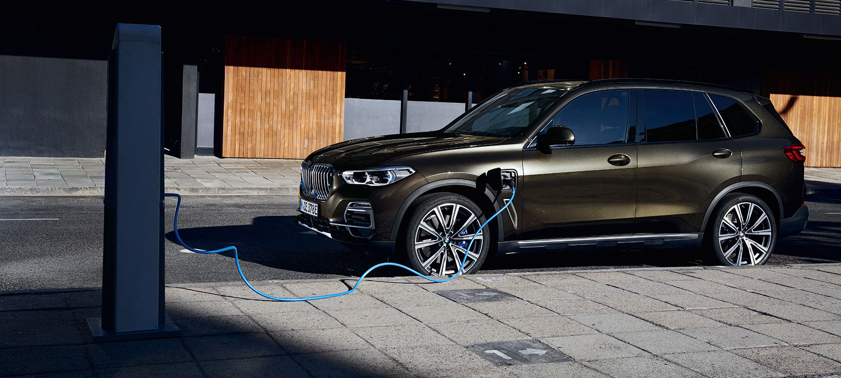 Plug-in hybrid BMW X5 xDrive45e sedd snett från sidan Plug-in hybrid BMW X5 xDrive45e sedd snett från sidan under laddning