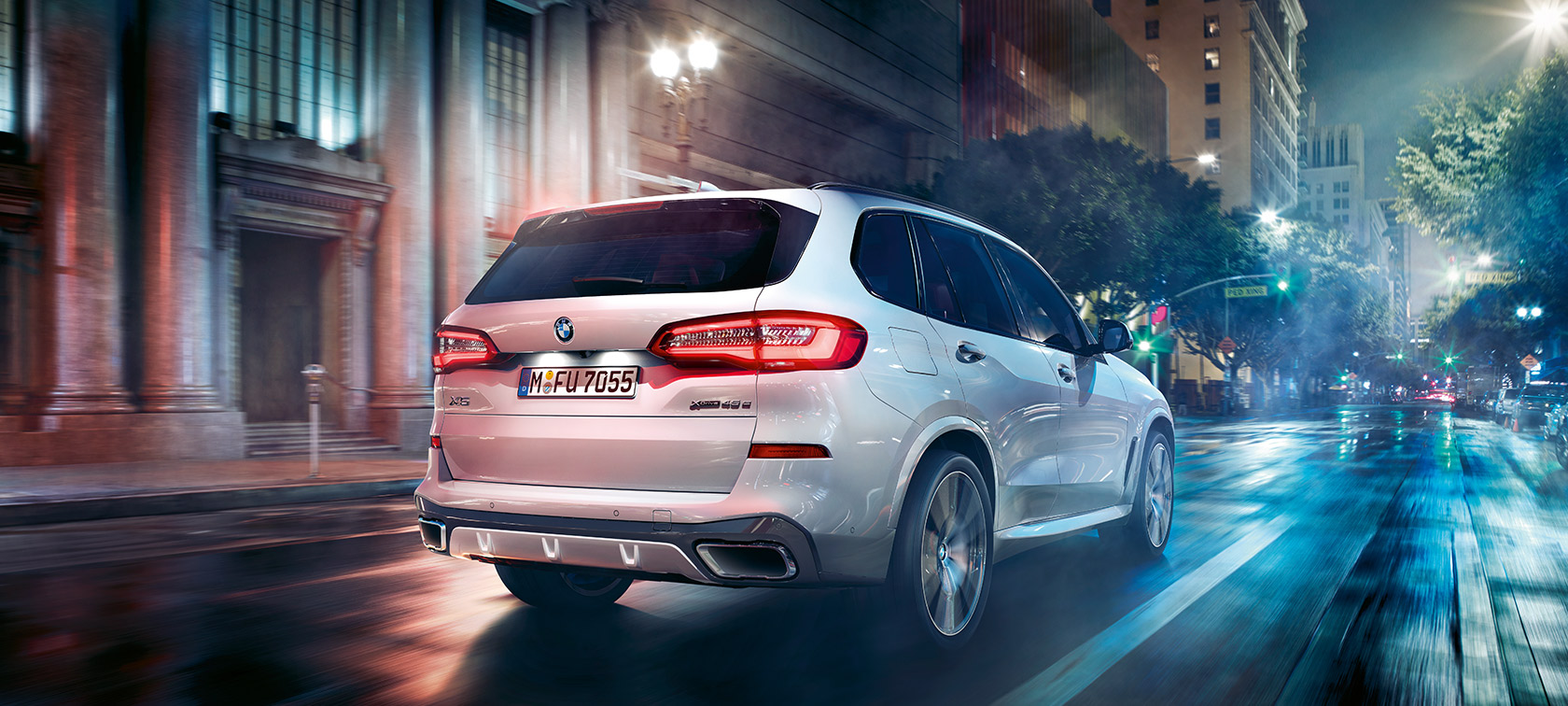 BMW X5 sedd snett bakifrån körandes BMW X5 G05 2021 Mineralvit metallic sedd snett bakifrån