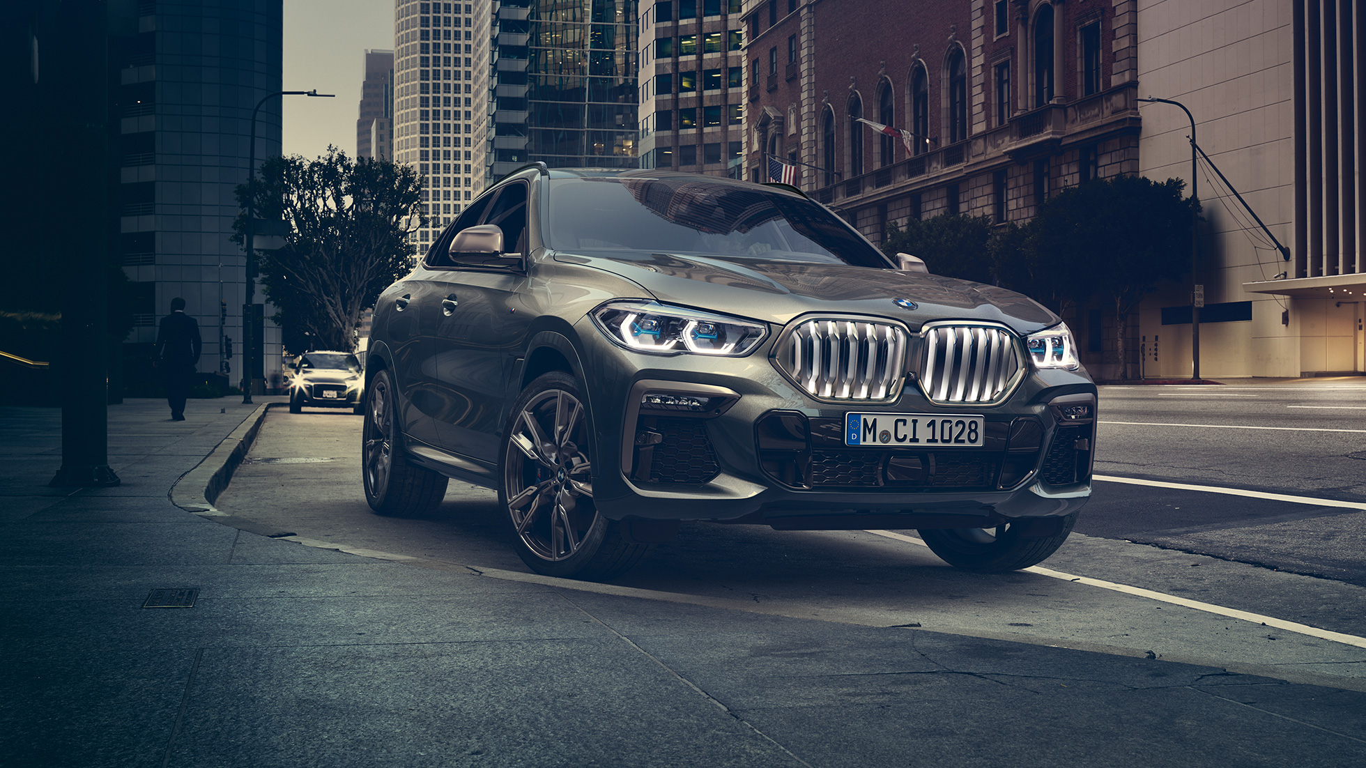 BMW X6, adaptivt M chassi Professional. BMW X6, trefjärdedelsvy framifrån framför stadsmiljö.