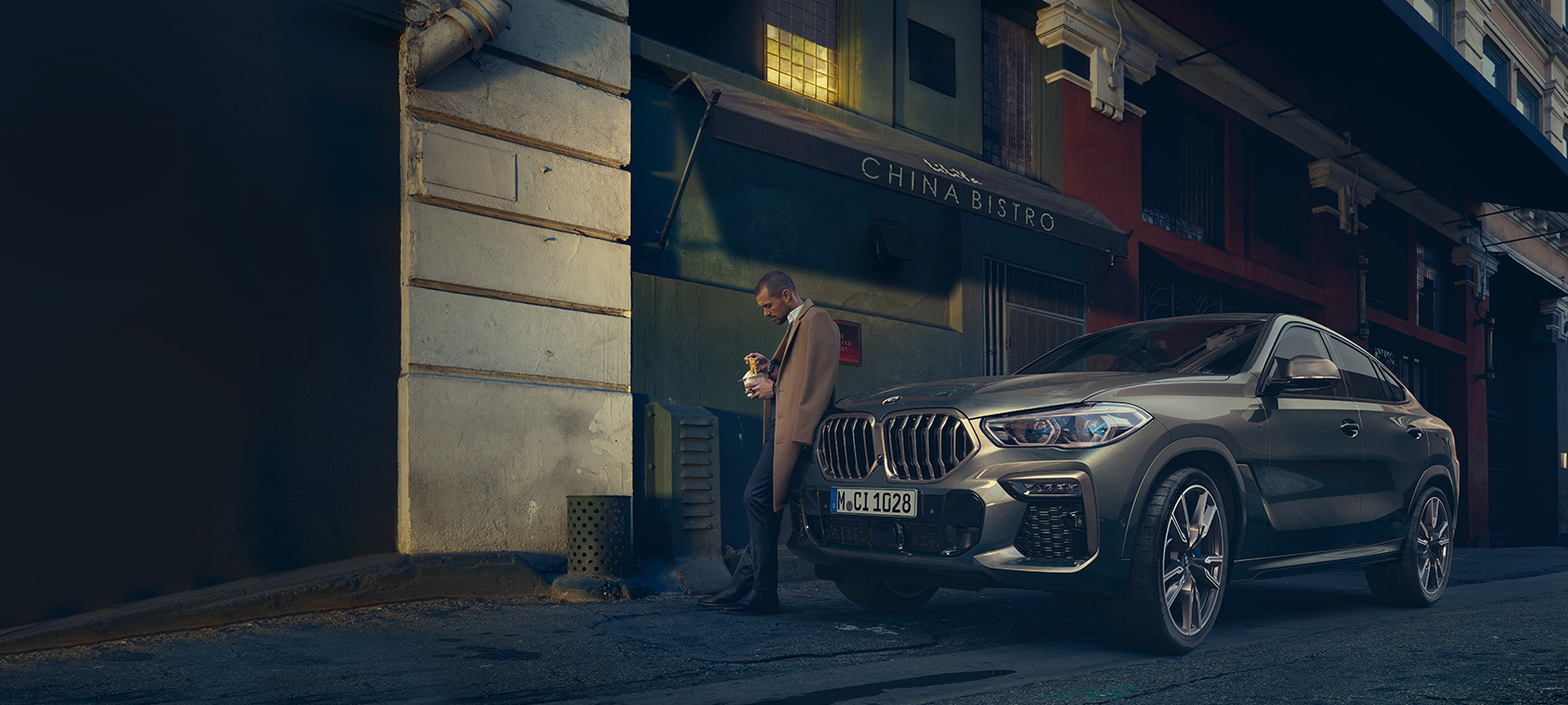 BMW X6 sedd snett bakifrån körandes BMW G06 2021 Manhattan metallic sedd snett bakifrån körandes