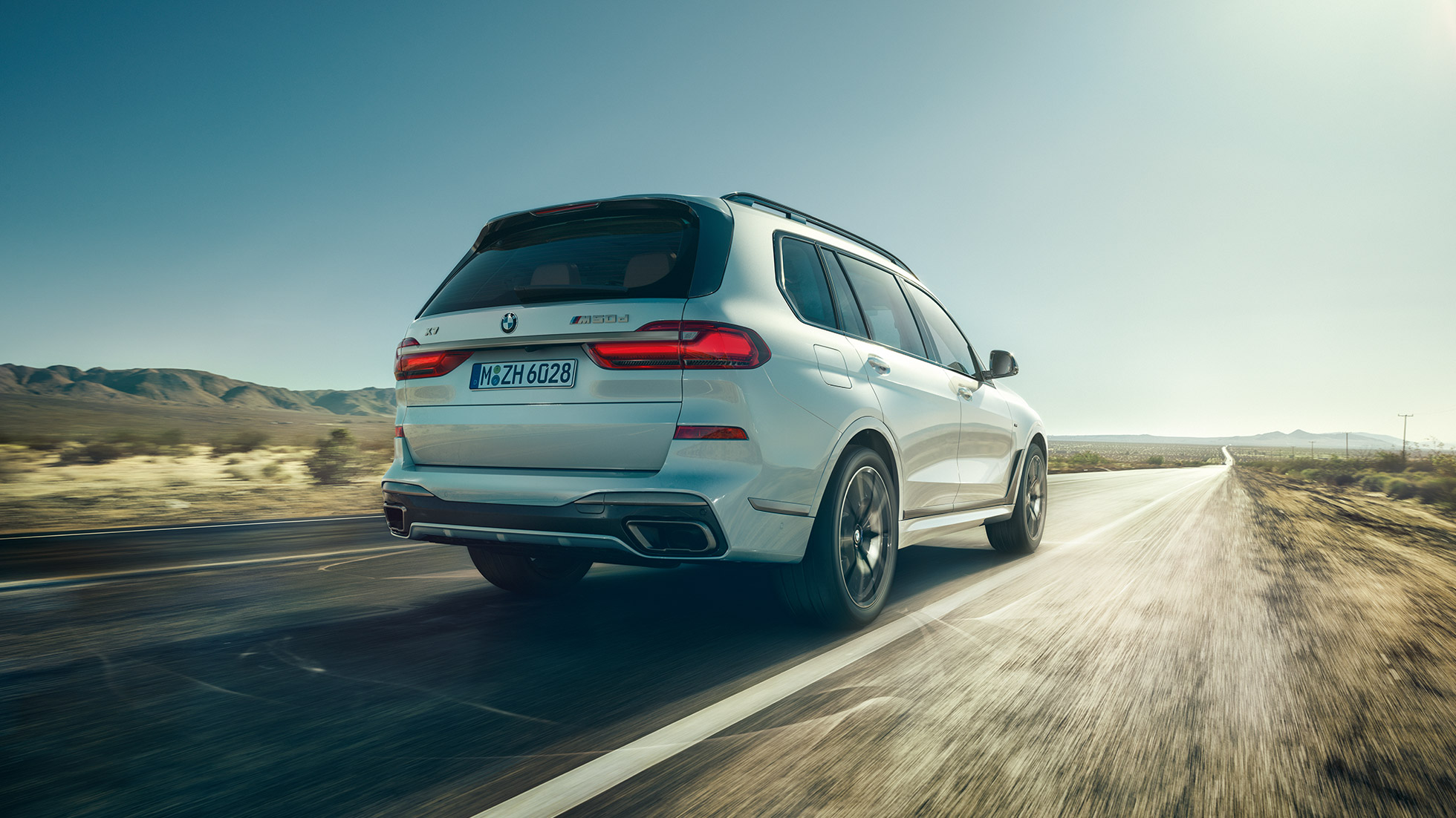 BMW X7 M50d, bakifrån BMW X7 M50d: Vit BMW X7 i rörelse, sedd bakifrån