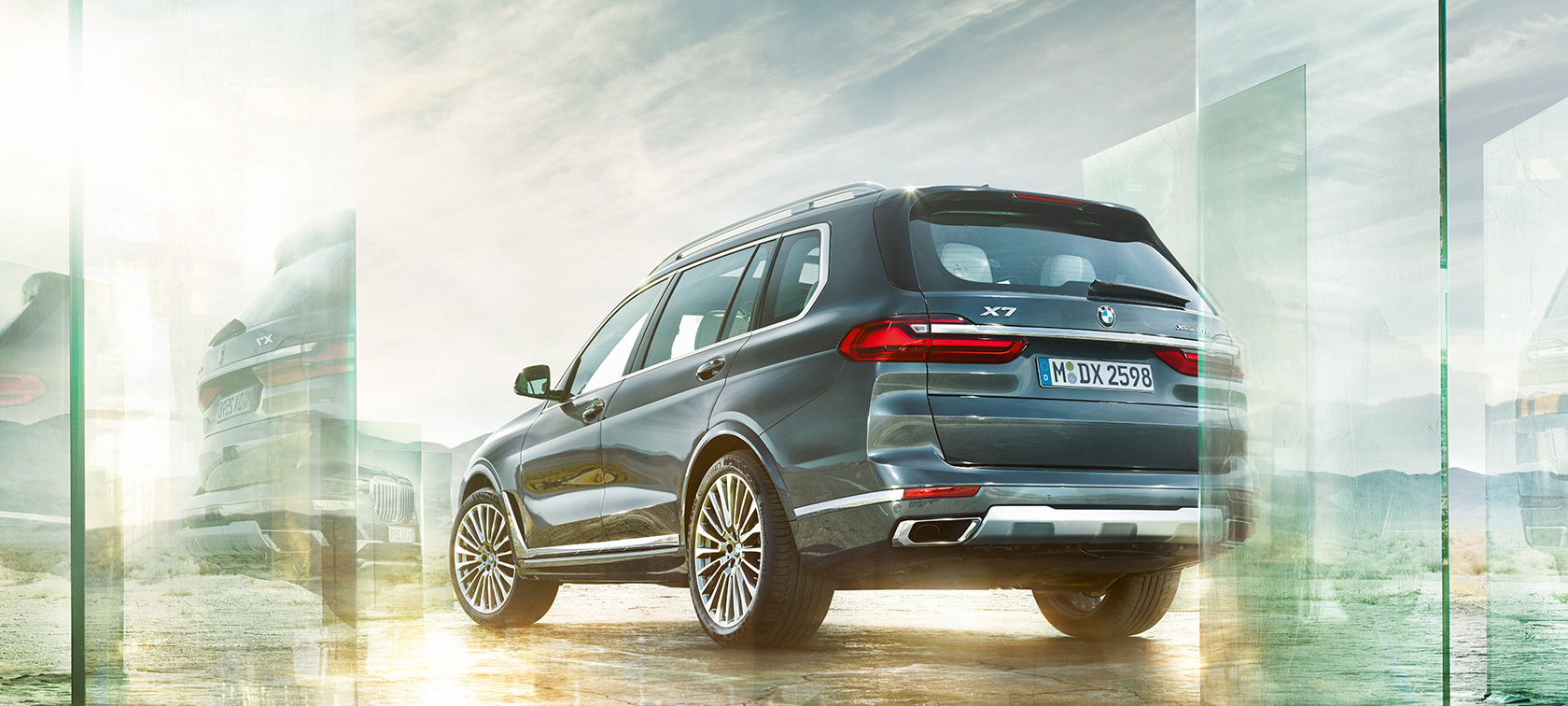 BMW X7, trefjärdedelsvy bakifrån. BMW X7 i Arctic Grey, Exteriör, trefjärdedelsvy bakifrån framför ökenbakgrund, G07 2019