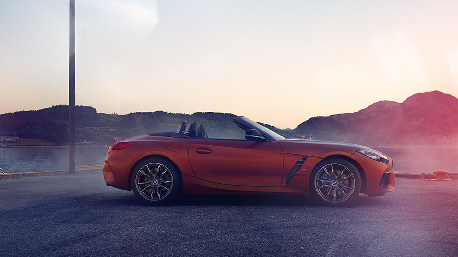 Orange BMW Z4 First Edition stillastående i kurva Orange BMW Z4 First Edition stillastående i en kurva framför bergspanorama