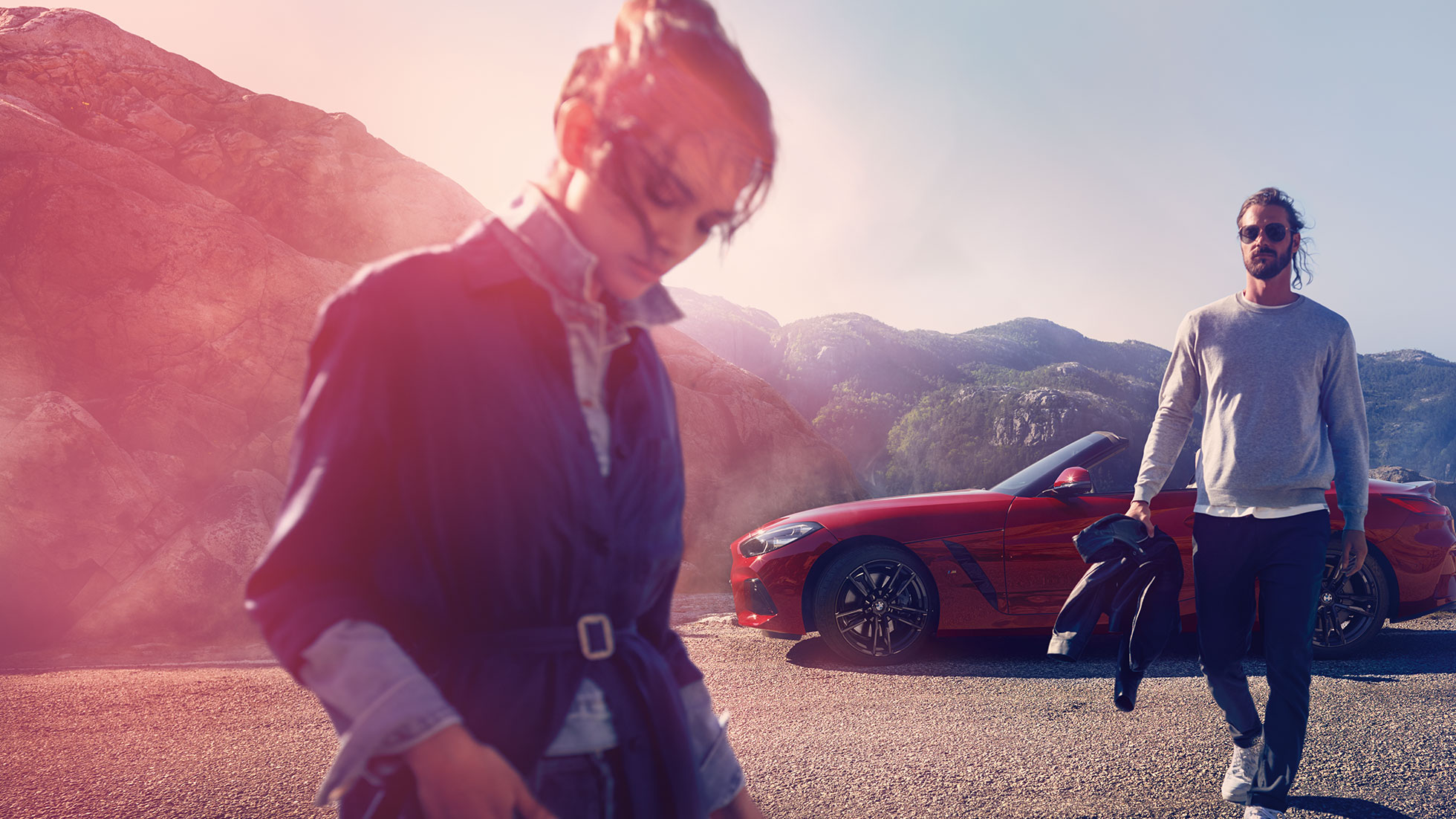 BMW Z4 Roadster framför ett bergslandskap Man och kvinna framför en BMW Z4 Roadster med berg i bakgrunden