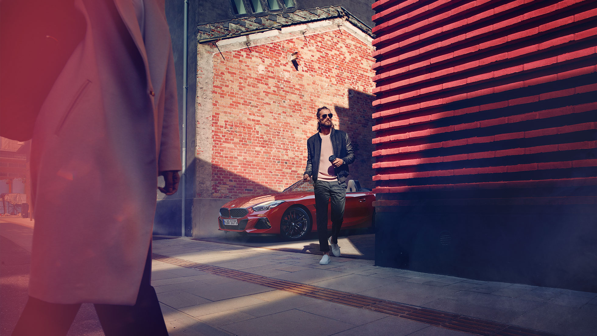 BMW Z4 Roadster på sidogata Man på en sidogata framför BMW Z4 Roadster