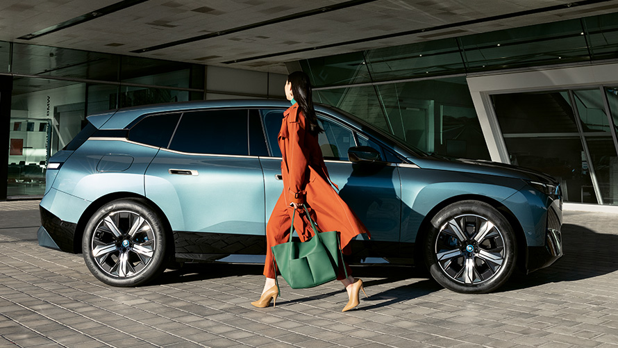 Använda BMW Digital Key BMW Digital Key användning BMW iX i20 sidvy med kvinna i förgrunden